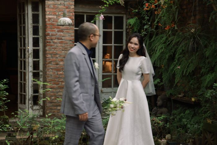 Hoa mỉm cười nhìn Sơn trước bức tường gạch
